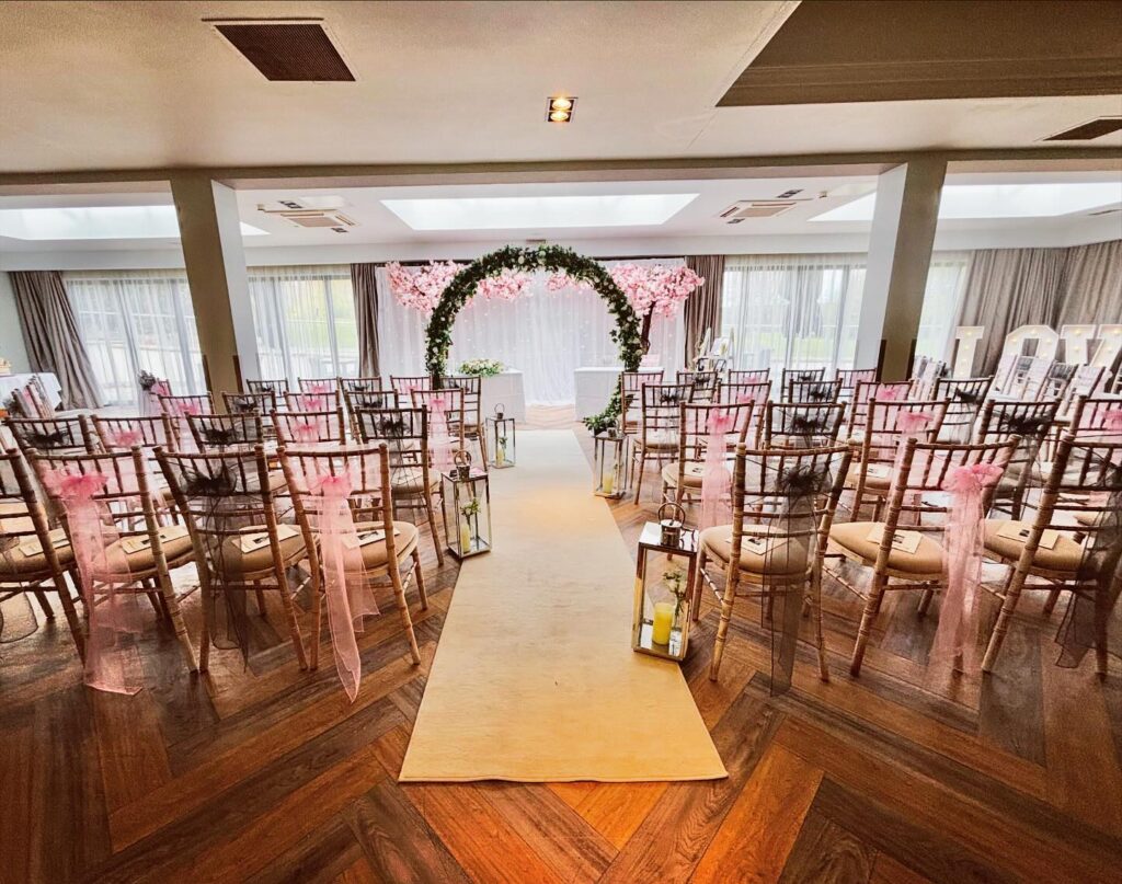 A ceremony room set out with a floral arch and dressed chairs