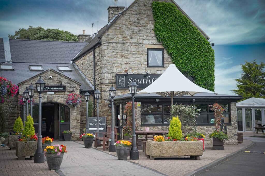 A stone country inn with flower tubs and a white canopy