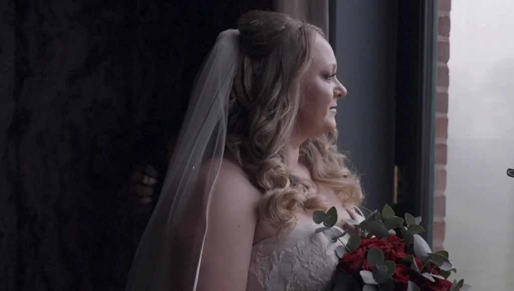 The bride waits by a window before the ceremony