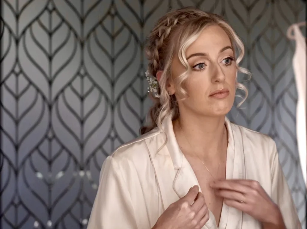 The bride gets ready in her satin robe, small white flowers in her braided hair
