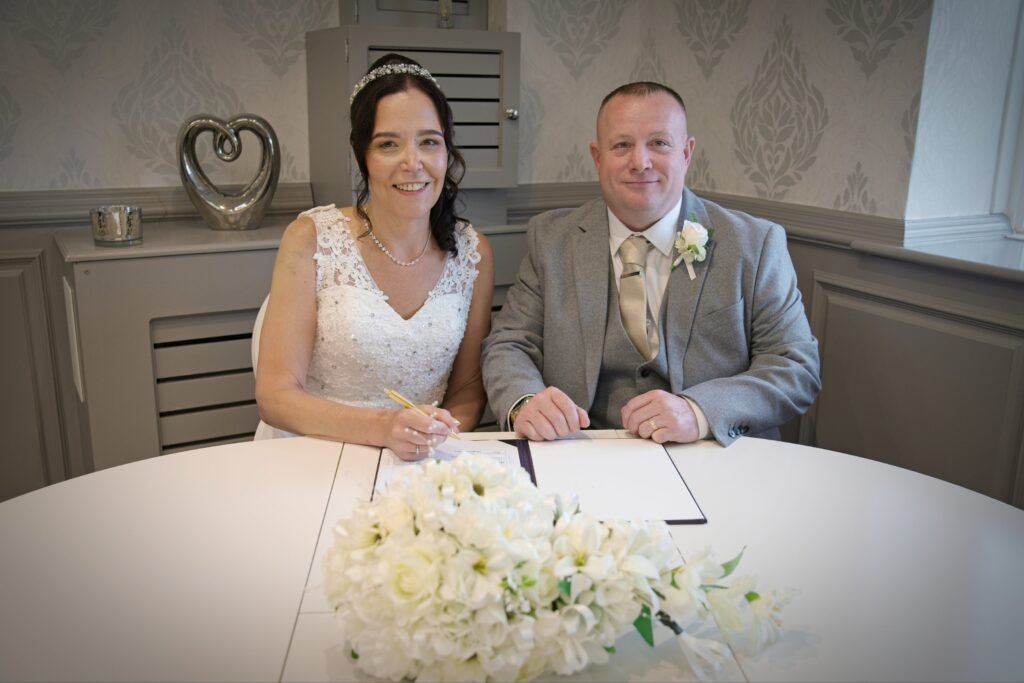 Bride and groom sign the register at a round table