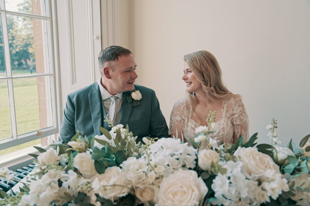 Bride and groom laugh together at a table of white flowers