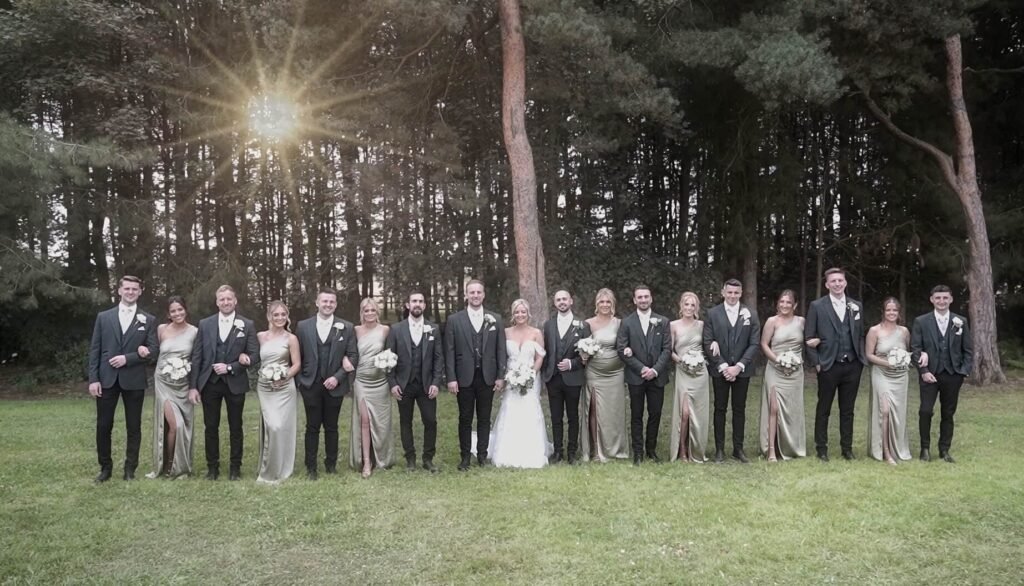 The bride, groom and wedding party in a pine wood at sunset
