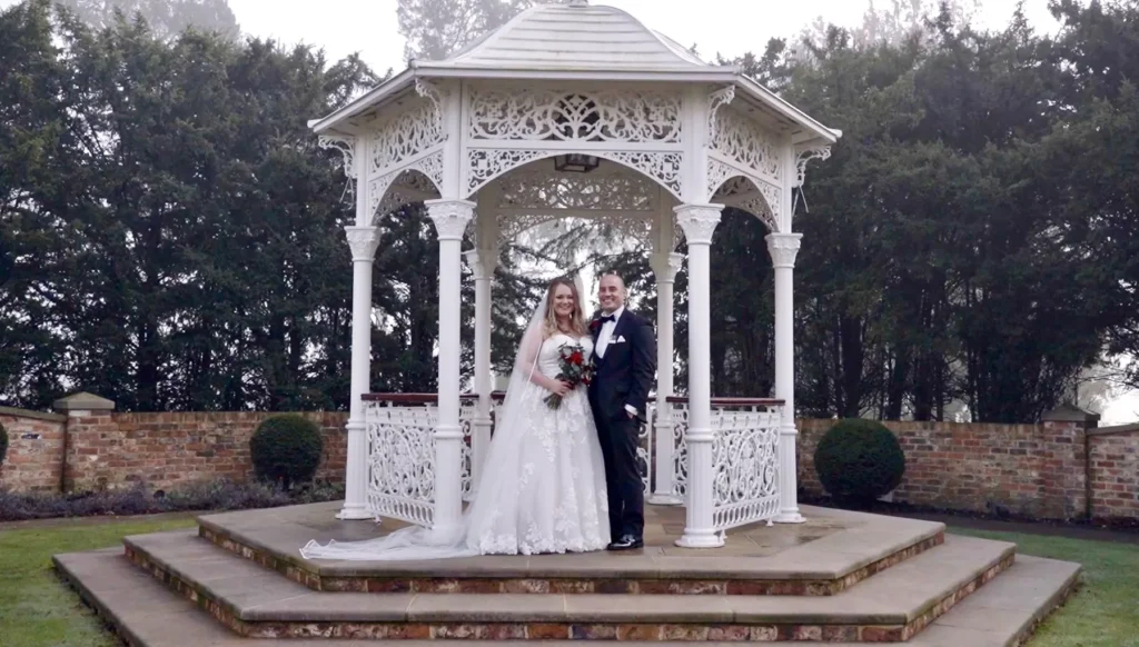 Bride and groom in a white ornate gazebo in a walled garden
