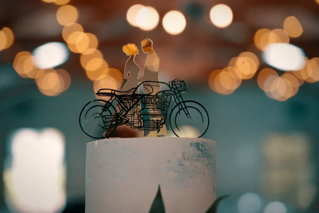 A cake topper of the couple and a motorbike, fairy lights glowing behind