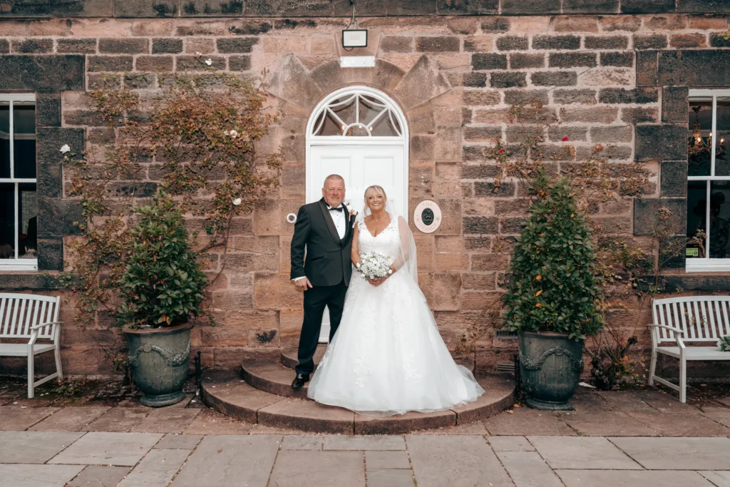 Bride and groom on the curved steps of a sandstone house, a fanlight above the door