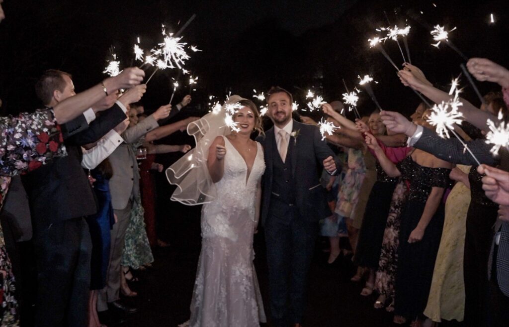 Bride and groom walking through a sparkler send-off at night