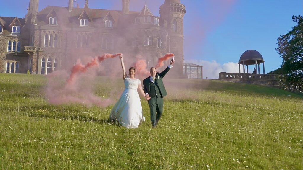 Bride and groom with a pink smoke flare on the lawn at Rushpool Hall