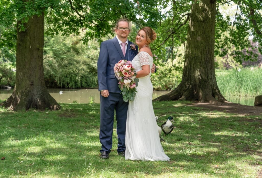 Bride and groom under the trees by a river