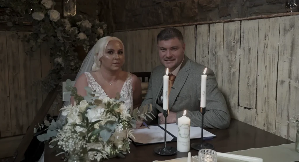 Bride and groom sign the register by candlelight
