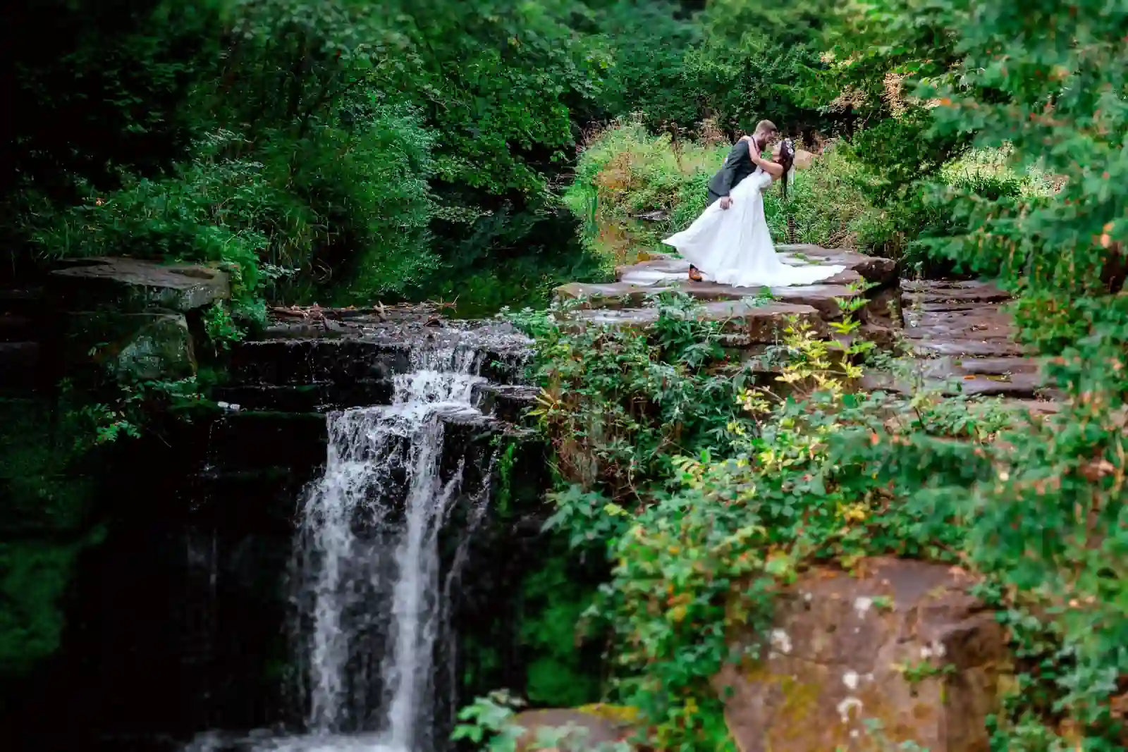 A wedding couple kisses on Jesmond Dene Waterfall