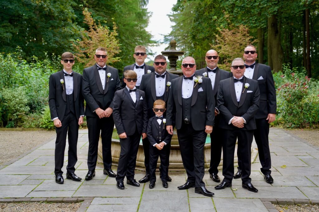 The groom and his groomsmen in sunglasses with two page boys