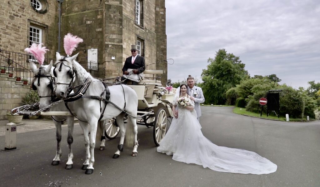 Bride and groom with a white horse-drawn carriage outside a hall