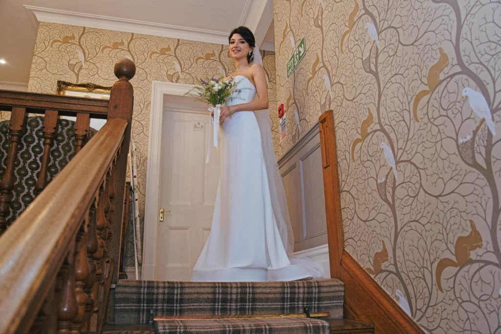 The bride on a staircase with patterned wallpaper